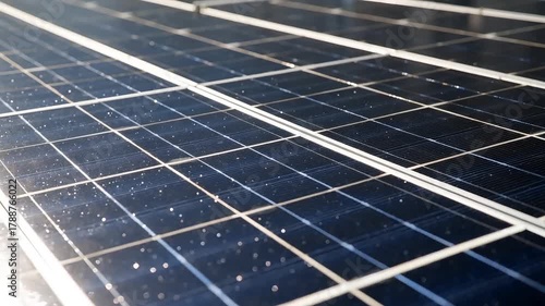 Extremely close-up detail of dark blue polycrystalline solar panel cells with thin white connecting lines and small raindrops on the surface in bright light