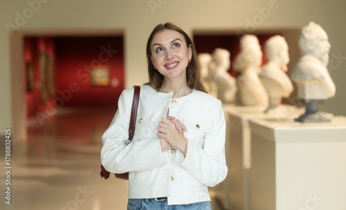 Young woman in a museum against the background of sculptures. Visitor at an art and sculpture exhibition