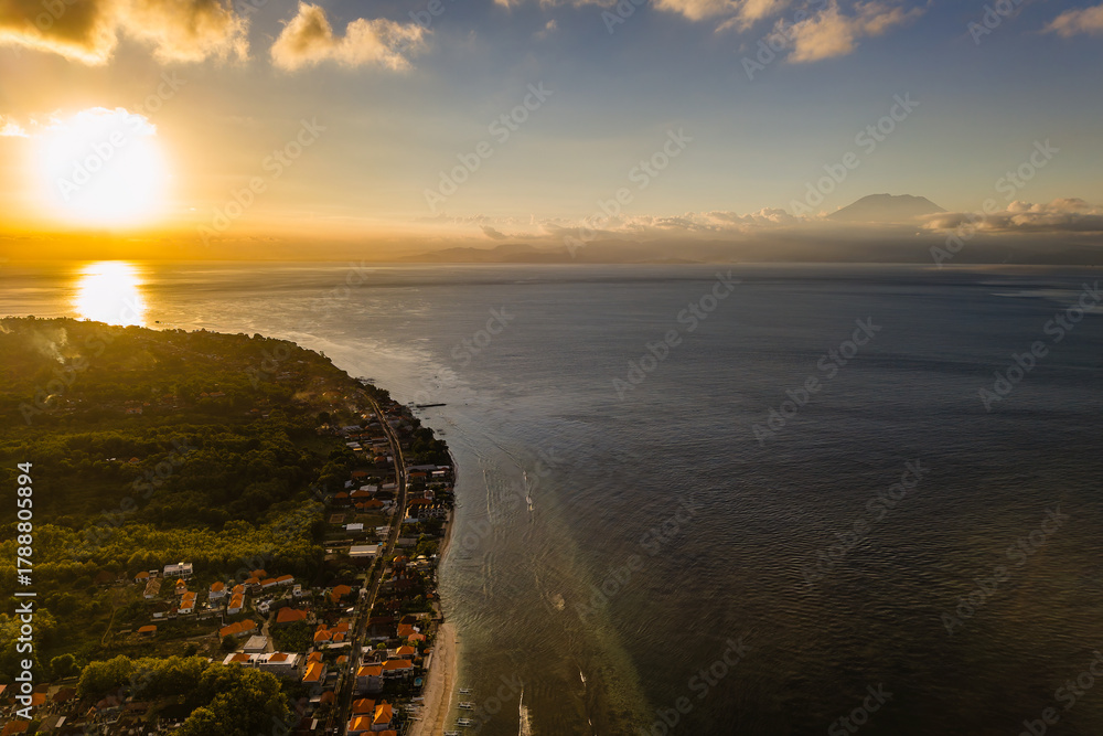 Obraz premium Aerial view of Nusa Penida coastline at sunset with Mount Agung volcano in distance