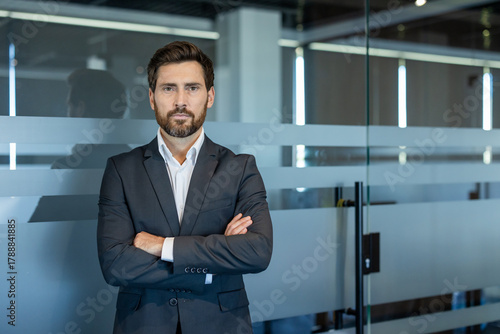 Confident businessman standing with arms crossed in a modern office environment, portraying professionalism, leadership, and expertise in a corporate setting