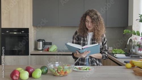 Female Reading Cookbook And Preparing Healthy Meal In Home Kitchen