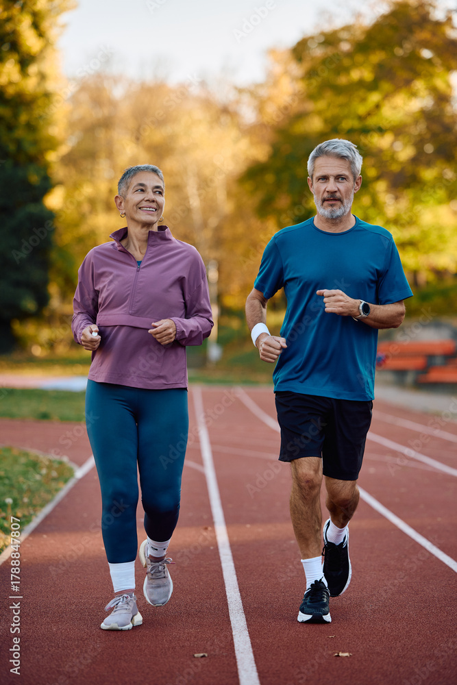 Obraz premium Mature couple of runners jogging in autumn day outdoors.