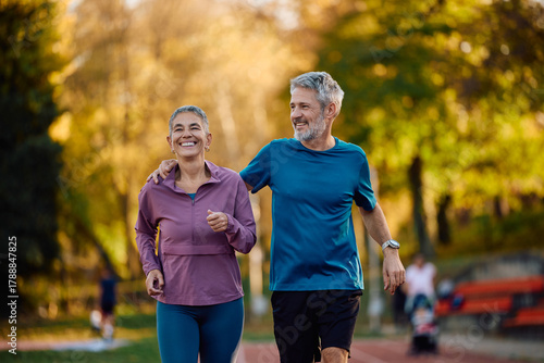 Happy mature sports couple running together in nature in autumn.