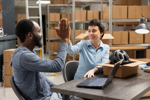 Papier peint Multiethnic workers team sharing a high five after achieving delivery goals, reflecting teamwork and success in a logistics center depot and storage room