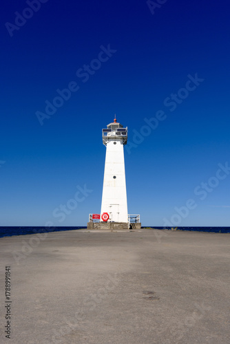 Low angle image of the concrete and stone pier leading to the Sodus Point Lighthouse on Lake Ontario in New York State on a beautiful afternoon