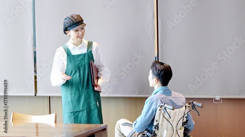 カフェスタッフが車椅子のお客様を案内しているシーン