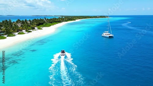 Aerial view of a tropical paradise with a speedboat, sailboat, island, and clear turquoise water
