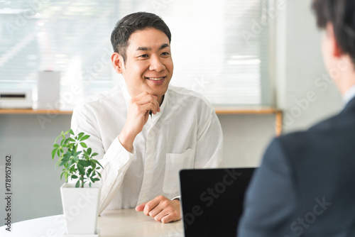 Foto Receptionist, middle-aged Asian man talking to a salesman at the counter