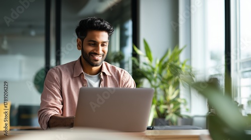 Wallpaper Mural Smiling indian business man working on laptop at home office. Young indian student or remote teacher using computer remote studying, virtual training, watching online education webinar at home office Torontodigital.ca