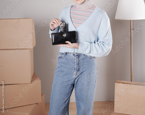 Young woman's body in a knitted sweater and jeans and her hand showing an elegant shiny black leather purse
