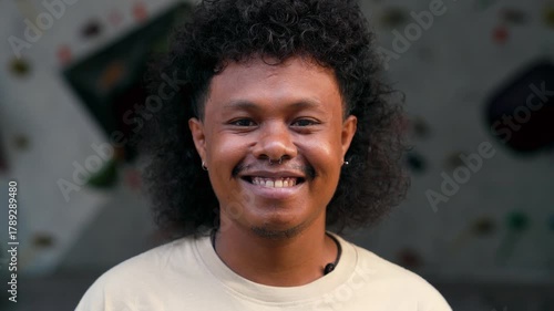 Portrait of Happy Asian Man Looking at Camera and Smiling on Abstract Background. Close Up View on Cute Face of One Indonesian Person Indoor. Charming Headshot of Optimistic Male at Cool Climbing Wall