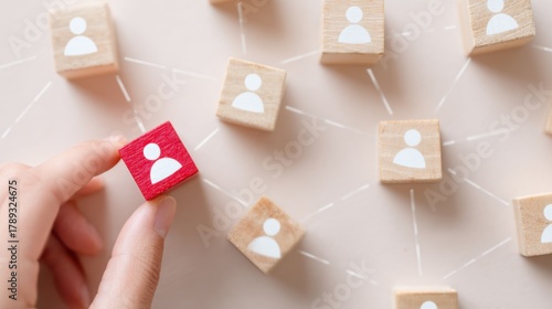 Strategic Networking: A hand carefully places a vibrant red cube among other neutral cubes connected by fine lines, symbolizing strategic networking and individual contribution within a larger system.