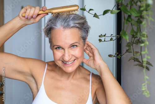 Portrait of a beautiful, smiling gray-haired European woman with a wooden comb. Concept anti-age.