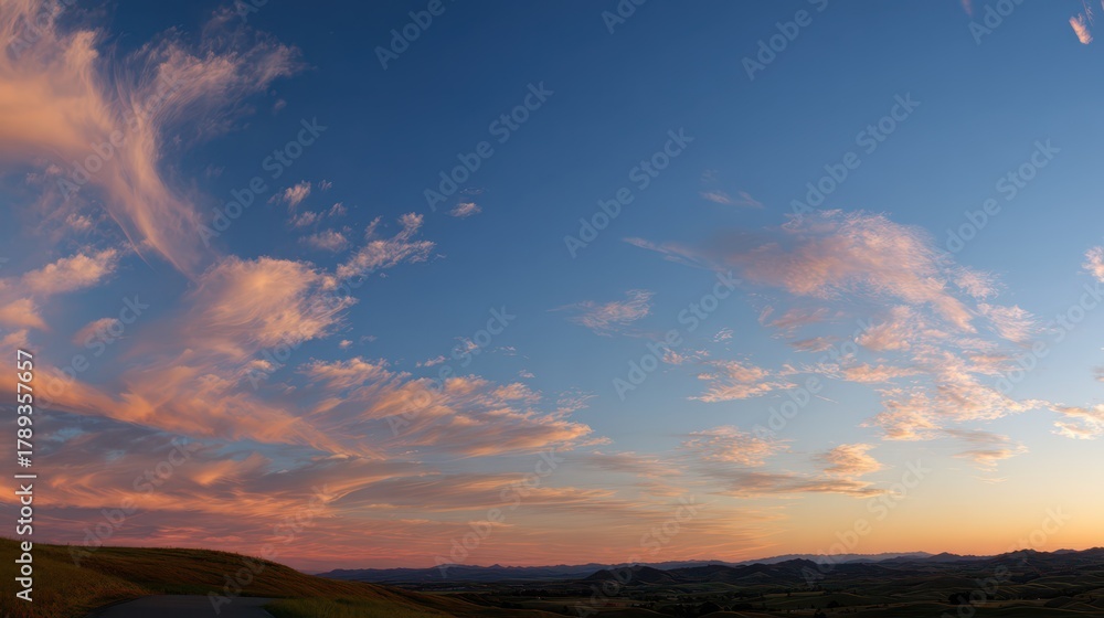 Obraz premium Calm blue sky with wispy clouds and a serene sunrise over a quiet landscape