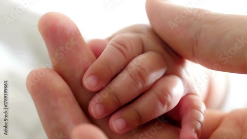 newborn baby holding mom hand, close-up view. mother takes care of the baby. close-up video of baby's hand. mom holds the hand of her newborn child.