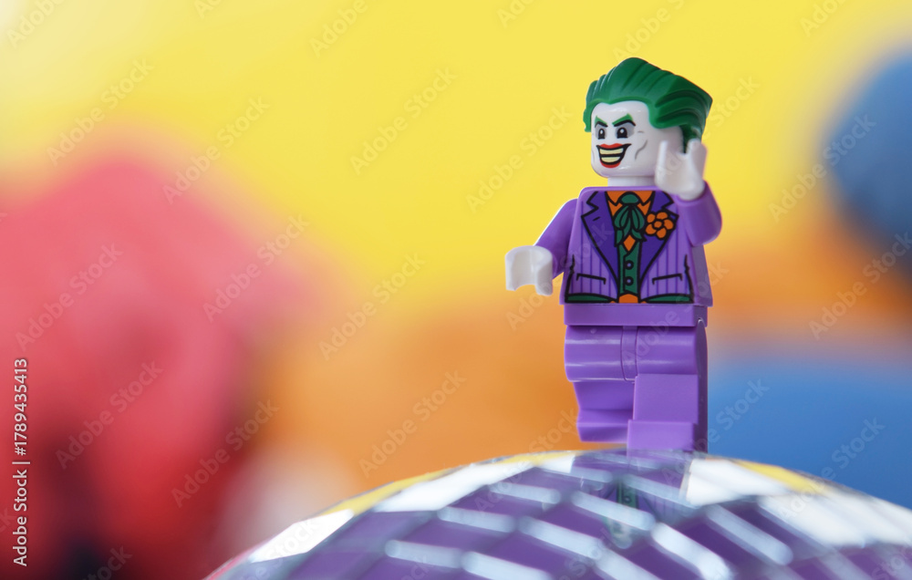 Naklejka premium Editorial illustrative image of lego minifigure of Joker in purple suit is walking.