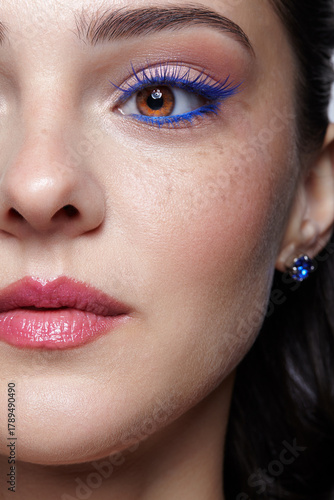 Closeup portrait of female face. Human woman half-face with unusual beauty blue eye lashes makeup.