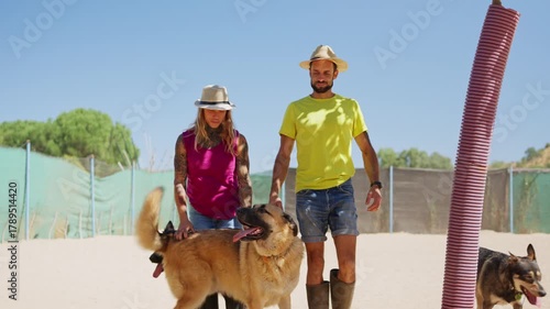 Young couple walking their dogs at an animal shelter in a sunny day