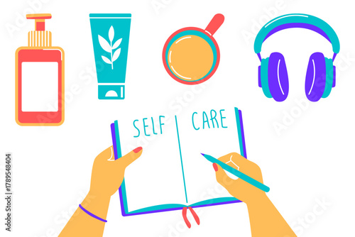 Hands writing "Self Care" in a journal surrounded by wellness items