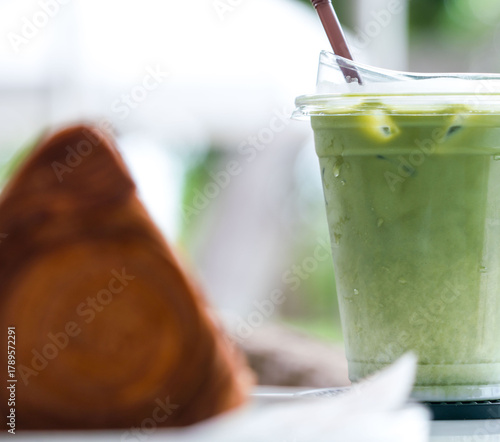 Iced matcha drink and croissant on table at cafe