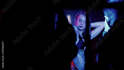 Sexy photo model takes a shower in a swimsuit, poses in front of a switch. Monochrome lighting, blue color.