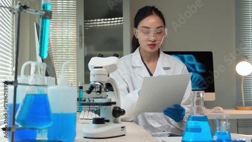 Asian female scientist writing research results in laboratory