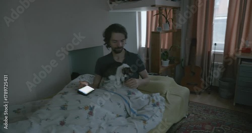 Man Waking up in Bed with Smartphone and Kitten. 4K 10-bit