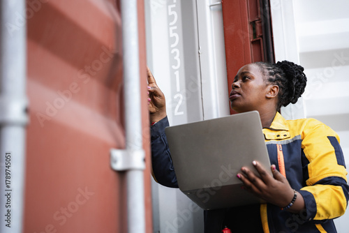African woman logistics workers use notebook computer checking container