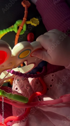 Close-up of a baby’s hand gripping a colorful sensory toy. Soft lighting highlights the small fingers and playful textures, creating a warm and emotional scene perfect for parenting themes, baby devel