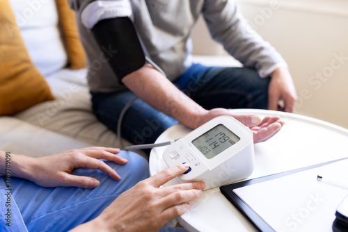 Cuadro en lienzo Nurse measuring blood pressure of senior man at home visit