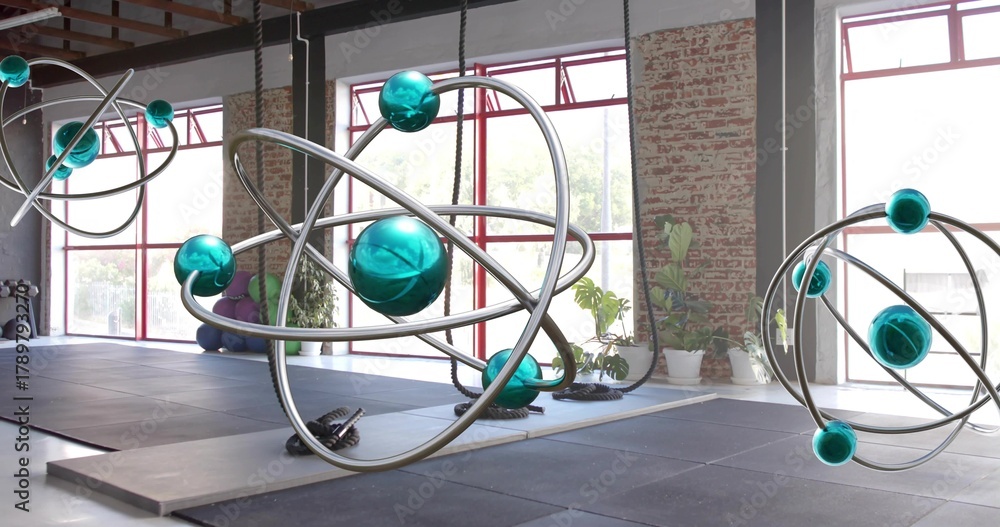 Fototapeta premium Hanging large orbital sculpture catching window light in warehouse studio, showing suspension ropes