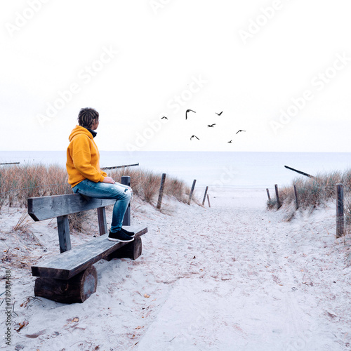 person is sitting on a bench at the beach, since in November