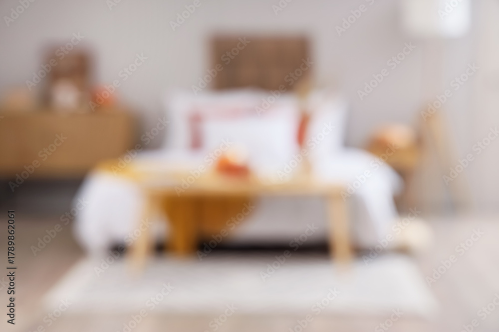 Obraz premium Interior of modern bedroom with soft bed, chest of drawers and pumpkins on coffee table, blurred view
