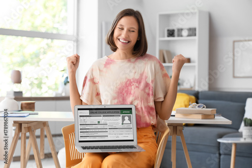 Excited young woman celebrating approved online college application on laptop...