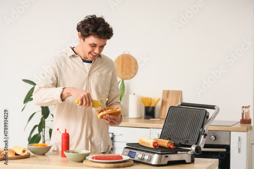 Young man cooking hot dog w...