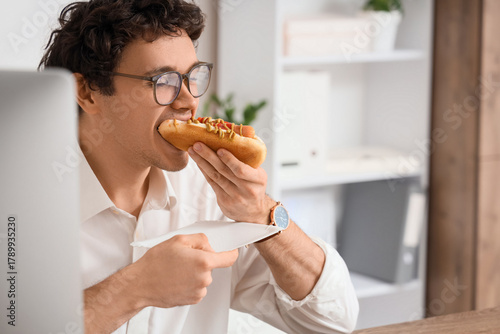 Young businessman eating ta...