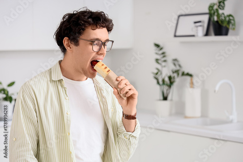 Young man eating hot dog in...