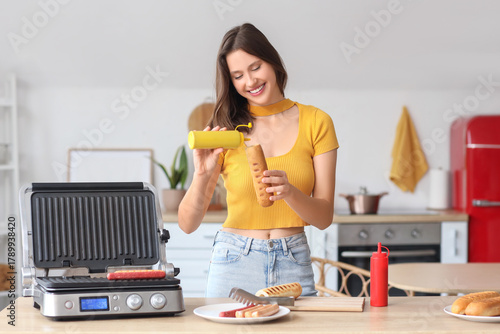 Young woman cooking hot dog...