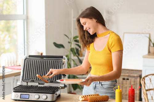 Young woman grilling sausag...