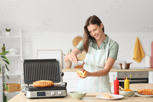 Young woman cooking hot dog...
