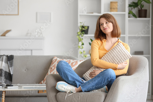 Young woman with pillow sitting in grey armchair at home Free Download Young woman with pillow sitting in grey armchair at home - GFXLoad