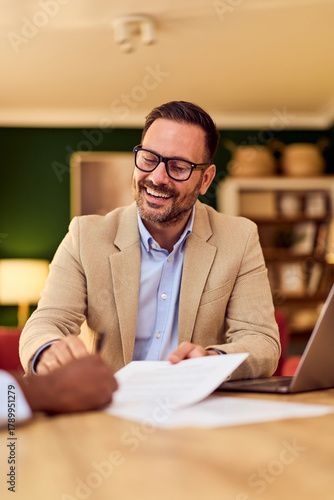 Wallpaper Mural Professional Man In Beige Blazer Meets Client For Paperwork, Laptop Review, And Friendly Discussion Torontodigital.ca