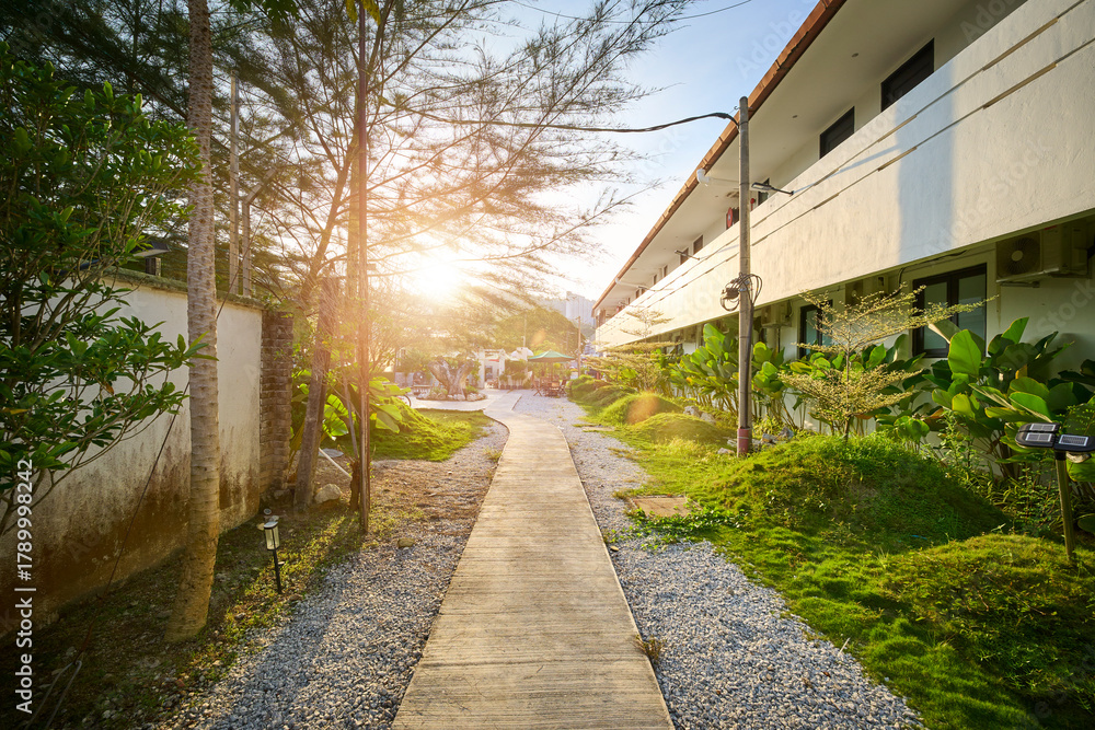 Obraz premium Resort garden walkway leading to hotel rooms at sunset