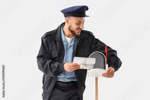 Handsome postman putting le...