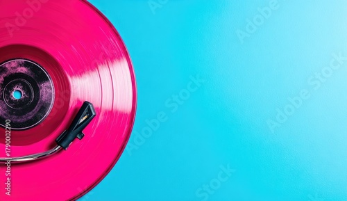 Pink vinyl record on a blue surface with a stylus.