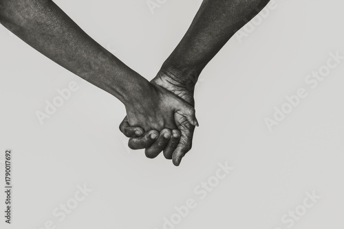 Woman and African American man holding hands on white background, closeup. Black and white toning