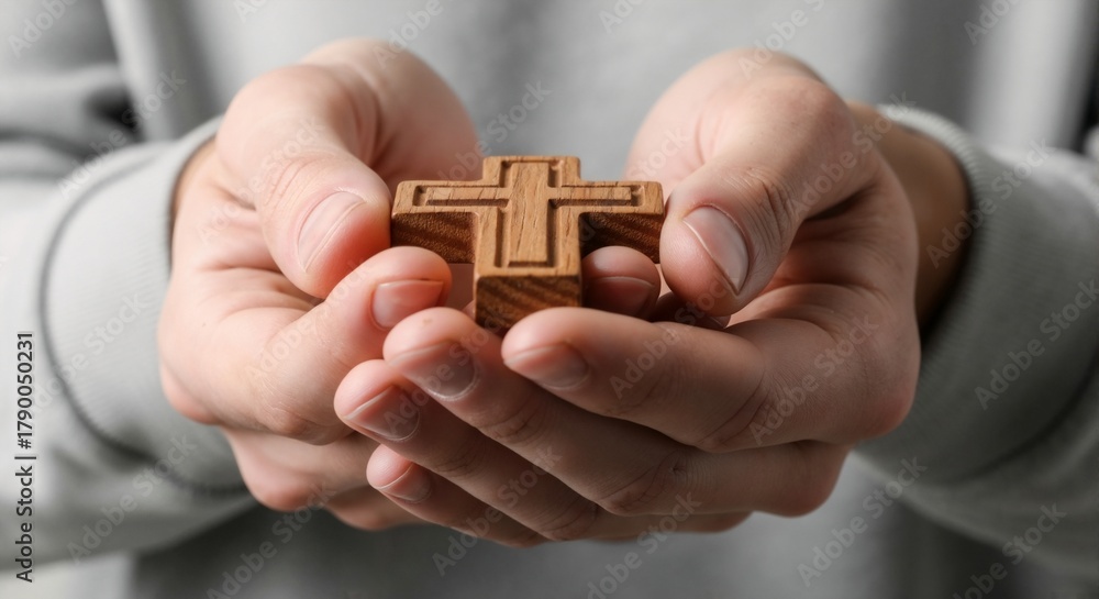 Fototapeta premium Hands gently cradling a wooden cross, symbolizing faith and spiritual devotion.