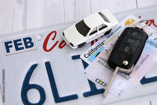 Remote control car keys on California license plate with driver license. Concept of driving in California. Reaching a driving permit