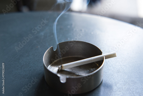 Close-up of a burning cigarette in an ashtray.