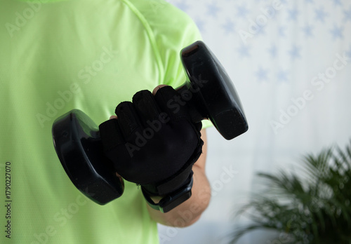 Close up of an unrecognizable man wearing a sports glove while lifting a dumbbell. Concept of strength, training, fitness detail, and active lifestyle